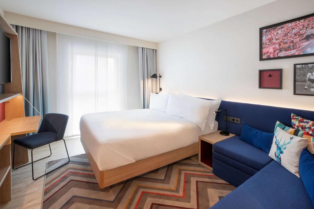 Habitación de hotel con cama y sofá azul en Hampton By Hilton Celle en Celle