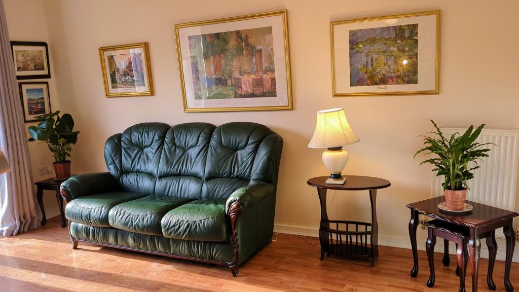 a living room with a leather couch and a lamp at Moray House in Church Gresley