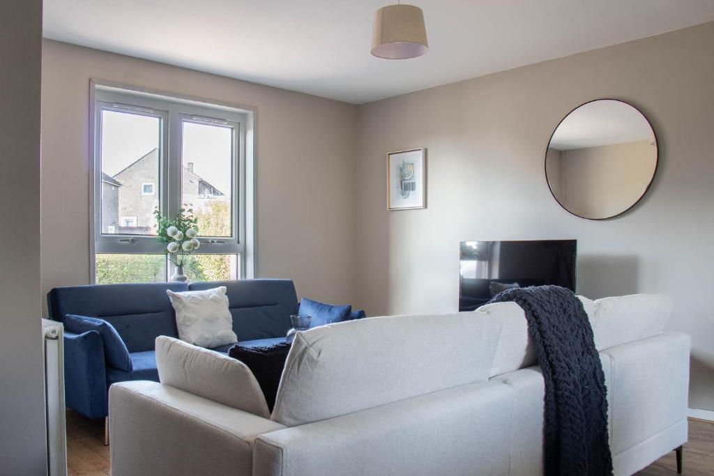 ein Wohnzimmer mit einem weißen Sofa und einem Spiegel in der Unterkunft Perth House in Clydebank