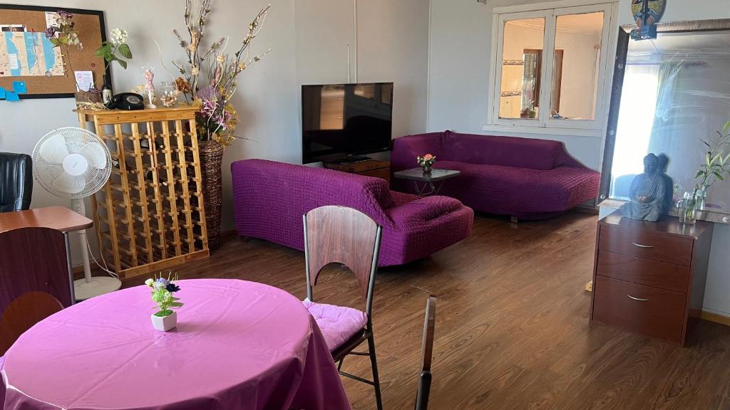 a living room with purple couches and a table at Ubicación central cabaña frente al mar in Tocopilla
