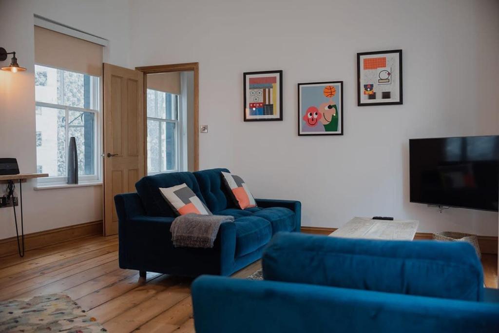 ein Wohnzimmer mit 2 blauen Stühlen und einem TV in der Unterkunft Spacious Norwich Lanes Apartment with Roof Terrace in Norwich