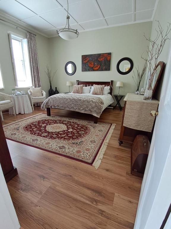 a bedroom with a bed and a rug on a wooden floor at The Porch suite @ Delavigne House in Riviersonderend