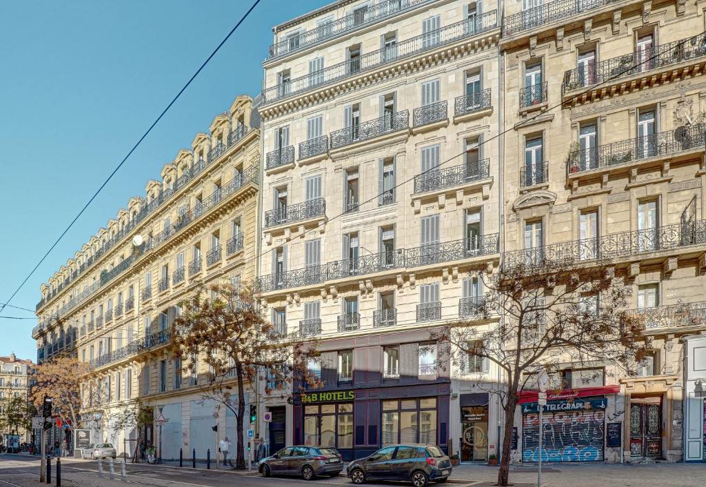 un grand bâtiment avec des voitures garées devant lui dans l'établissement B&B HOTEL Marseille Centre Vieux Port, à Marseille