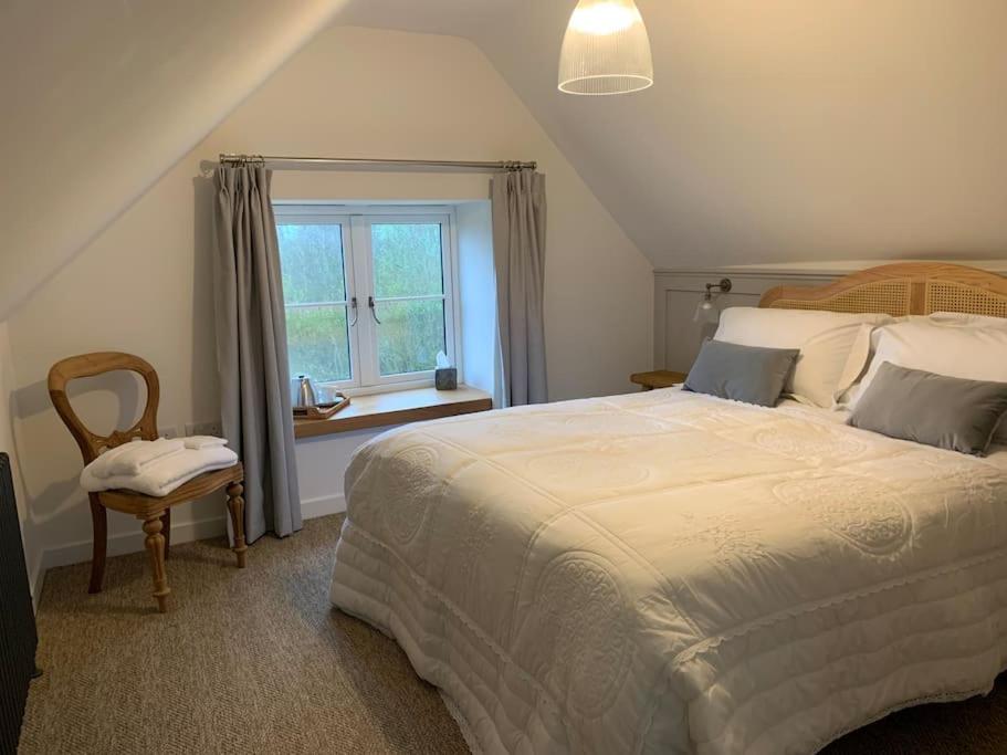 sypialnia z dużym łóżkiem i oknem w obiekcie Stunning East Devon Cider Barn w mieście Northleigh