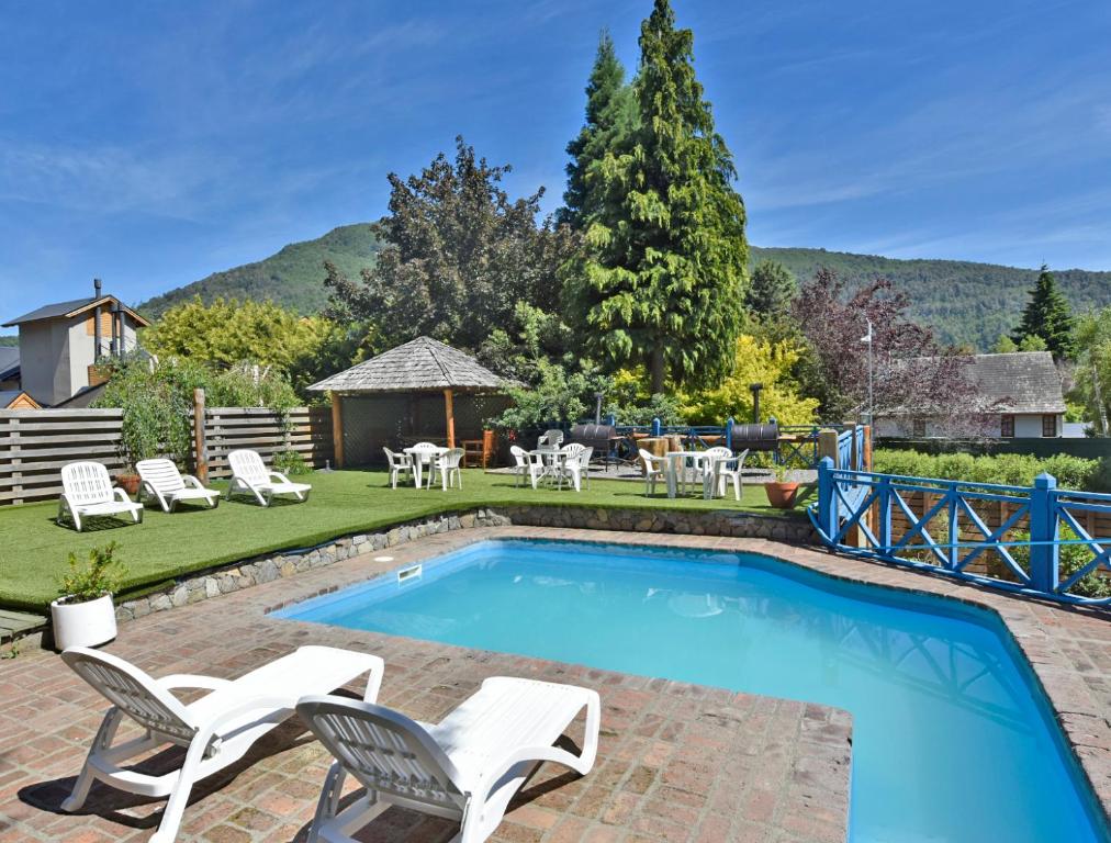 a swimming pool with chairs and a patio with a table at Plaza Mayor in San Martín de los Andes