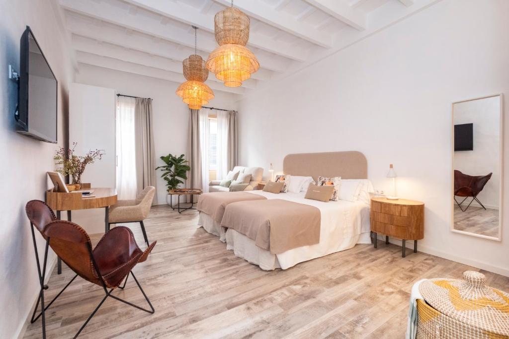 ein weißes Schlafzimmer mit einem Bett, einem Schreibtisch und Stühlen in der Unterkunft Encant de Alaior Boutique Hotel in Alaior