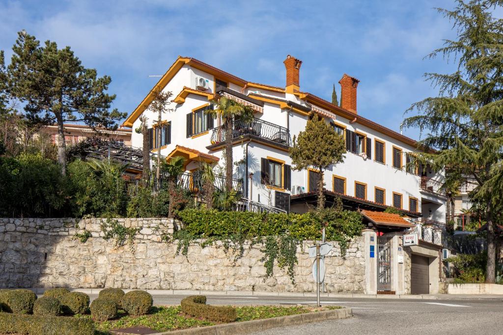 a large white house on a stone wall at Camelia & Martina apartments in Opatija