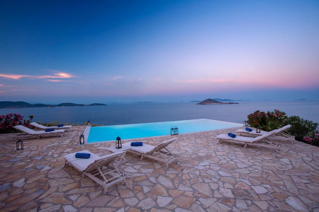 una piscina con sillas y vistas al océano en Villa Sophia Patmos, en Patmos