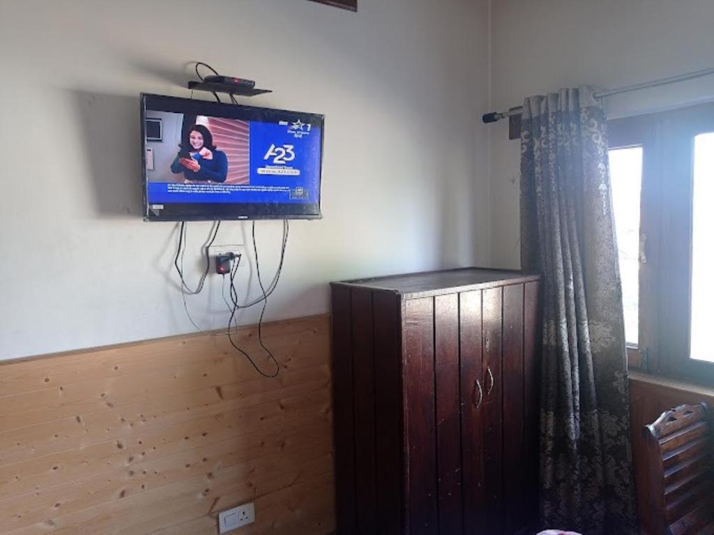 a flat screen tv on a wall in a living room at Pinez Guest House , Anantnag in Anantnāg