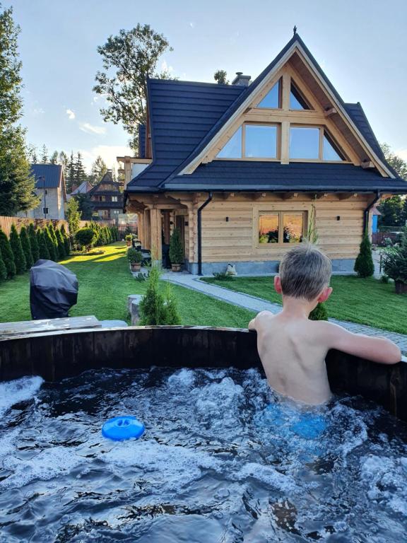 a young boy in a hot tub in front of a house at Nosalowski Wypas in Zakopane