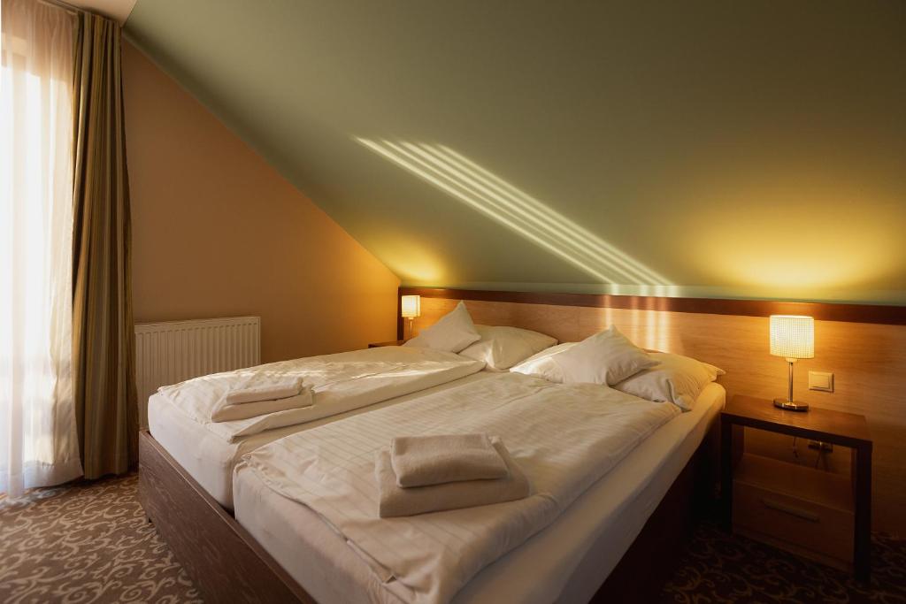 a bedroom with a large bed with white sheets and pillows at Hotel Green in Dolný Kubín