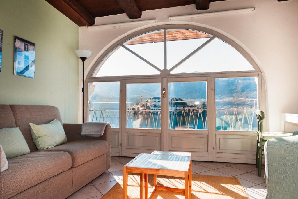 a living room with a couch and a large window at -Ortaflats- Appartamento l'Isola in Orta San Giulio