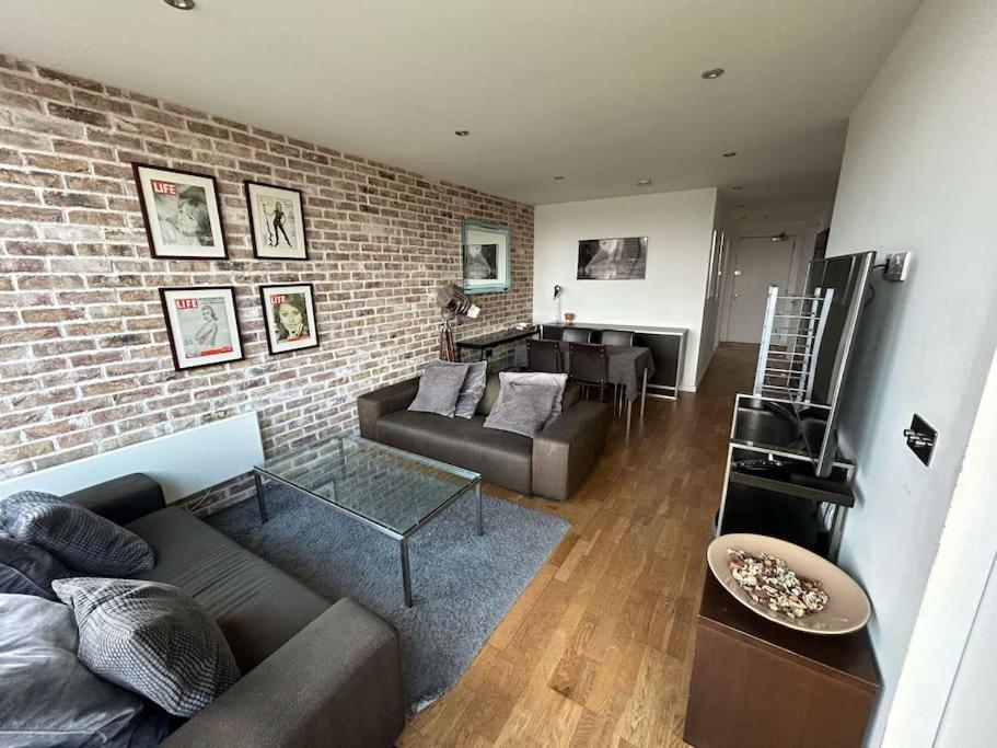 a living room with a couch and a brick wall at Modern 2-bed Apartment 5 mins from London Bridge in London