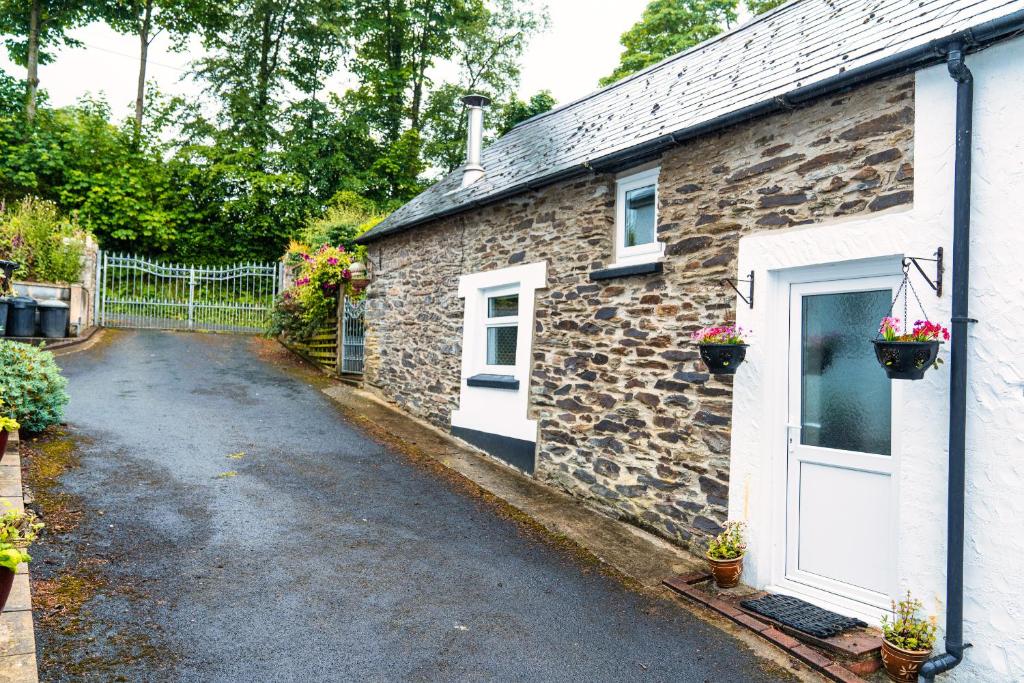 a stone house with a white door and a driveway at Upper Cottage Drefach Felindre in Cwm-pengraig