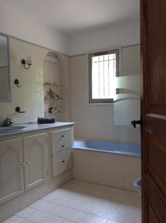 een badkamer met een bad, een wastafel en een raam bij La Suite, Les Hautes Roches in Collobrières