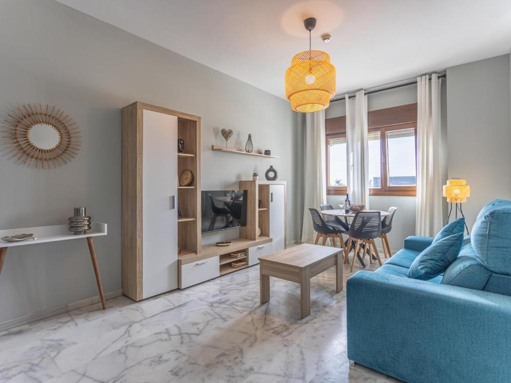 ein Wohnzimmer mit einem blauen Sofa und einem Tisch in der Unterkunft Lux Bormujos - Vacacional Sevilla in Bormujos