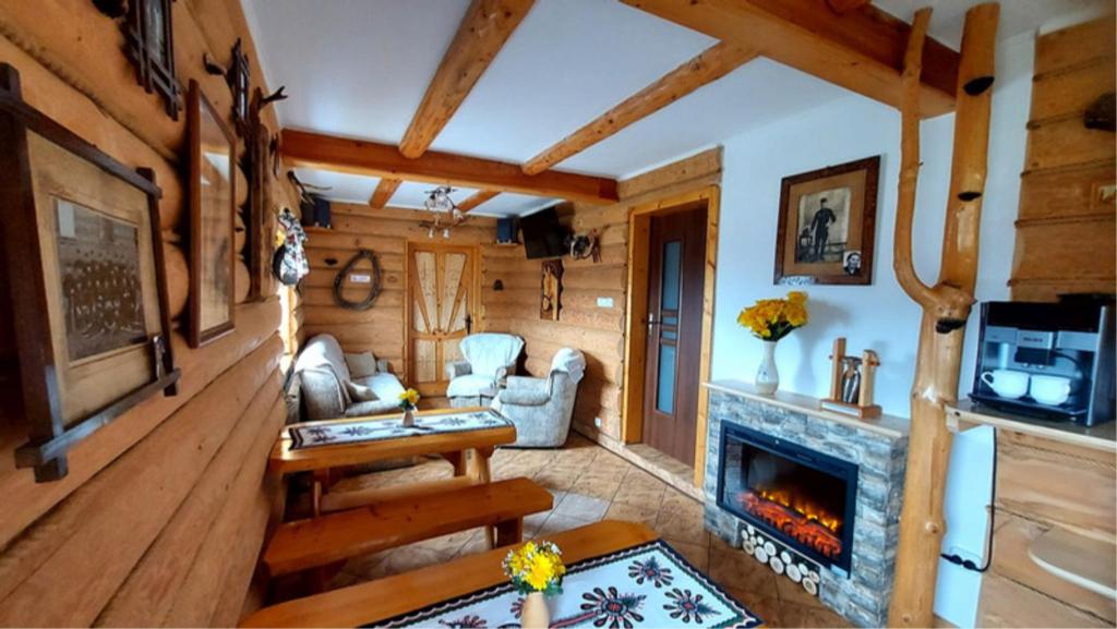 a living room with a fireplace in a log cabin at Willa Pośrednia in Zakopane