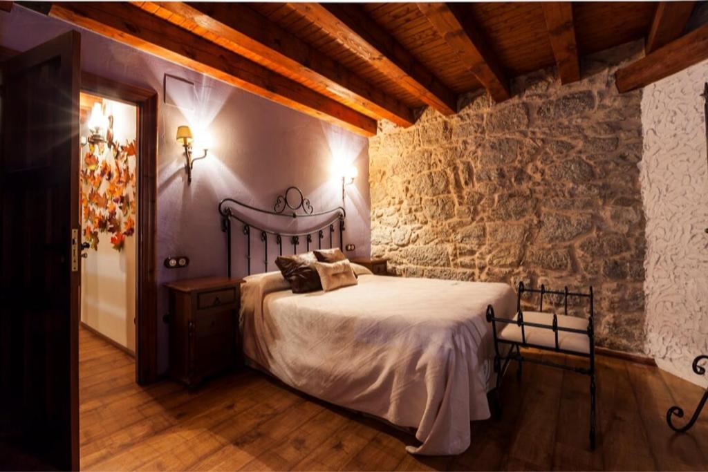 a bedroom with a bed and a stone wall at Auténtica casa rural con encanto by beBalmy in Sorihuela