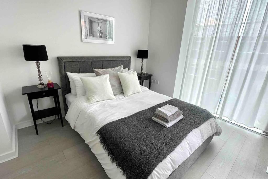 a bedroom with a large bed with two lamps and a window at Spacious 2 Bedroom Apartment With Balcony In Jewellery Quarter, Birmingham City Centre in Birmingham