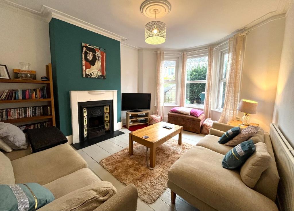 a living room with two couches and a fireplace at Charming cottage retreat with garden - sleeps 12 in Bristol