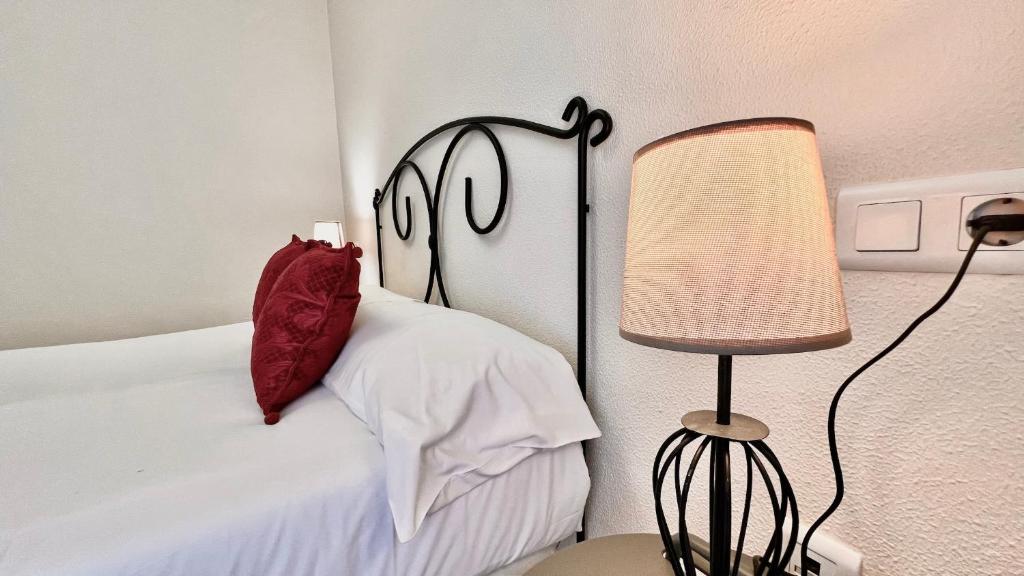 a bedroom with a bed with a red pillow and a lamp at SibsSanlucar Reina del Centro - Parking in Sanlúcar de Barrameda