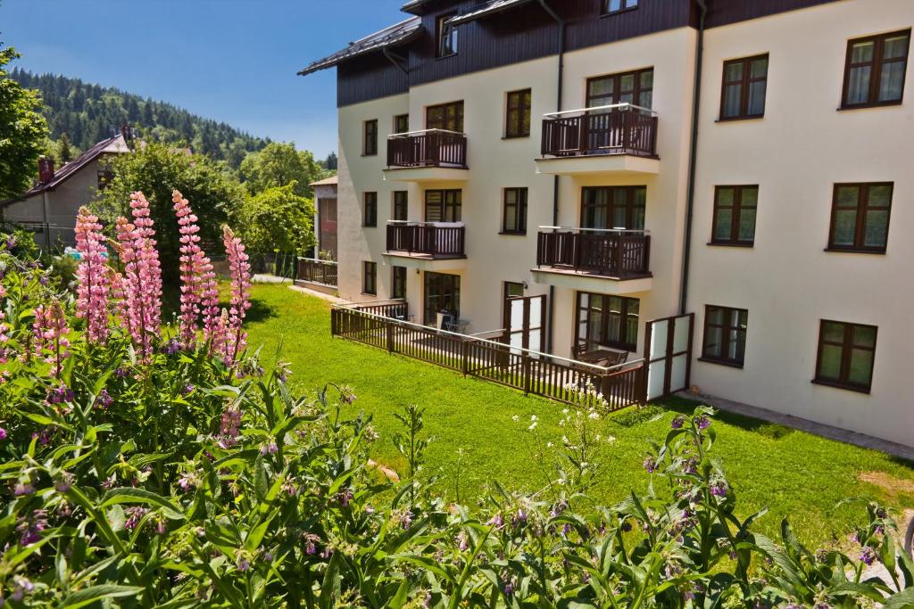 an apartment building with pink flowers in the foreground at Apartamenty City Center Cicha 8 in Krynica Zdrój