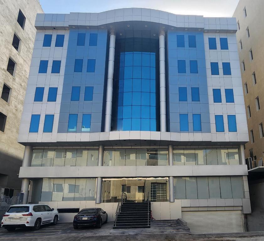 un edificio azul con coches estacionados frente a él en Yan Furnished Apartments, en Al Khobar
