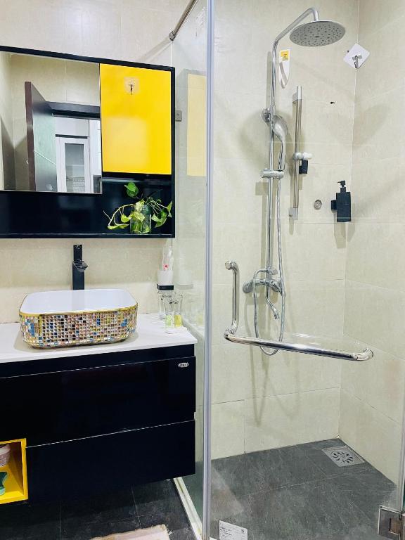 y baño con ducha acristalada y lavamanos. en Vinhomes Green Bay G30332, en Hanói
