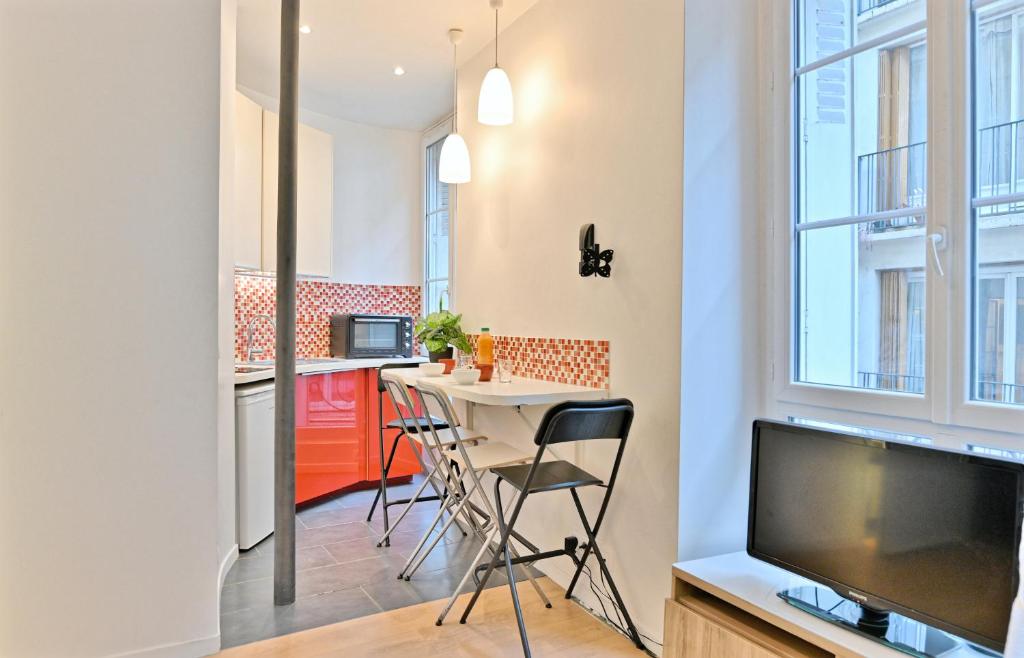 - une cuisine avec une table et une télévision dans la chambre dans l'établissement Appartement au cœur du Marais - IV, à Paris