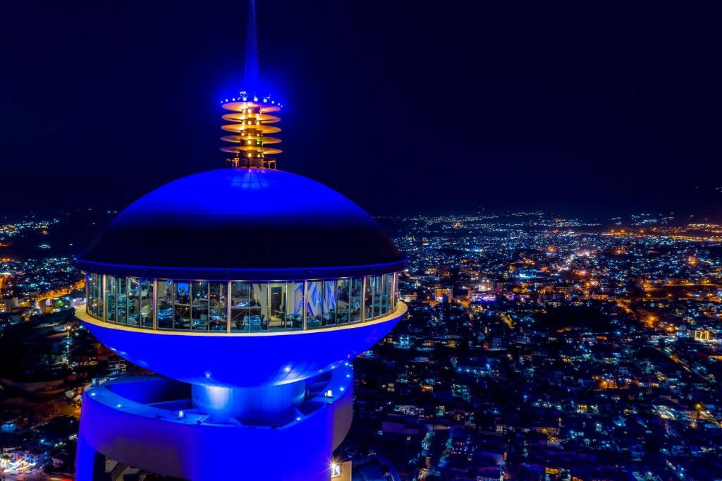 スライマーニーヤにあるGrand Millennium Sulaimaniの夜の街を背景にした青い管制塔