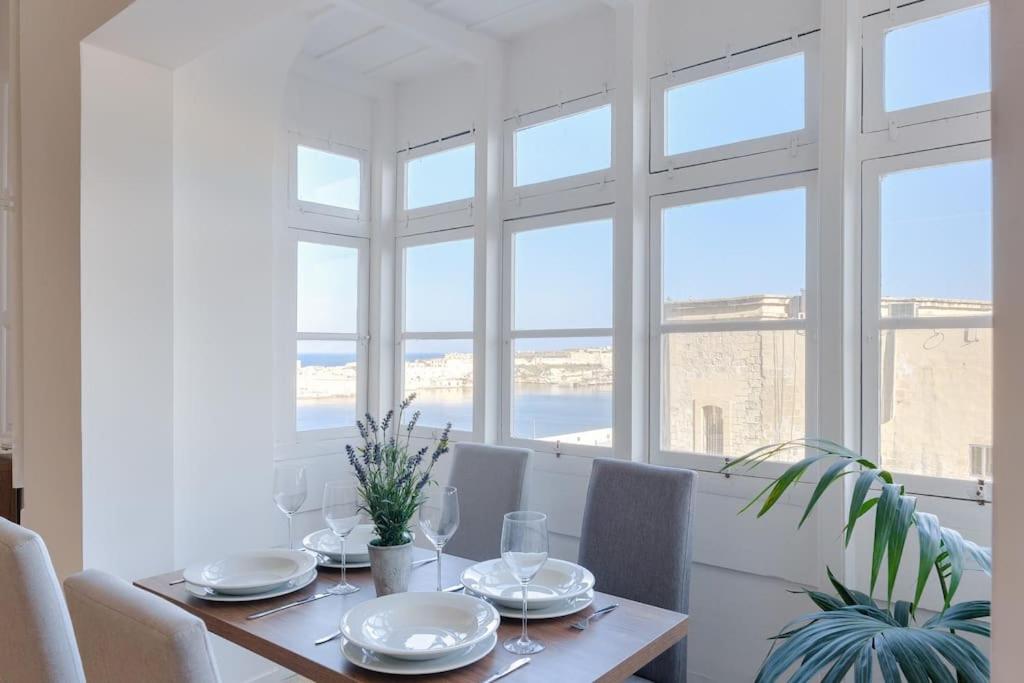 d'une salle à manger avec une table, des chaises et des fenêtres. dans l'établissement Rare Seaview Condo in Valletta 2, à La Valette
