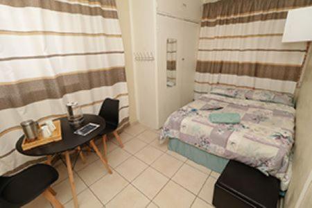 プレトリアにあるLas Palmas Day & Night Guest Houseのベッド、テーブル、椅子が備わる小さな客室です。