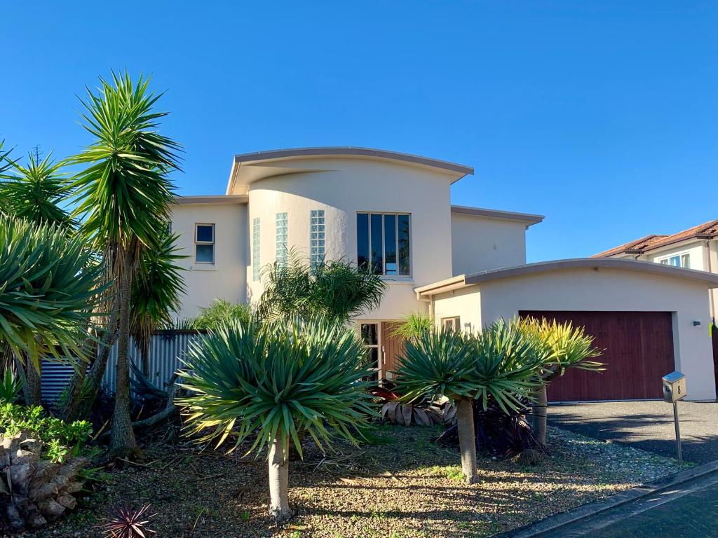 a white house with palm trees in front of it at Amazing Seaview House in Auckland