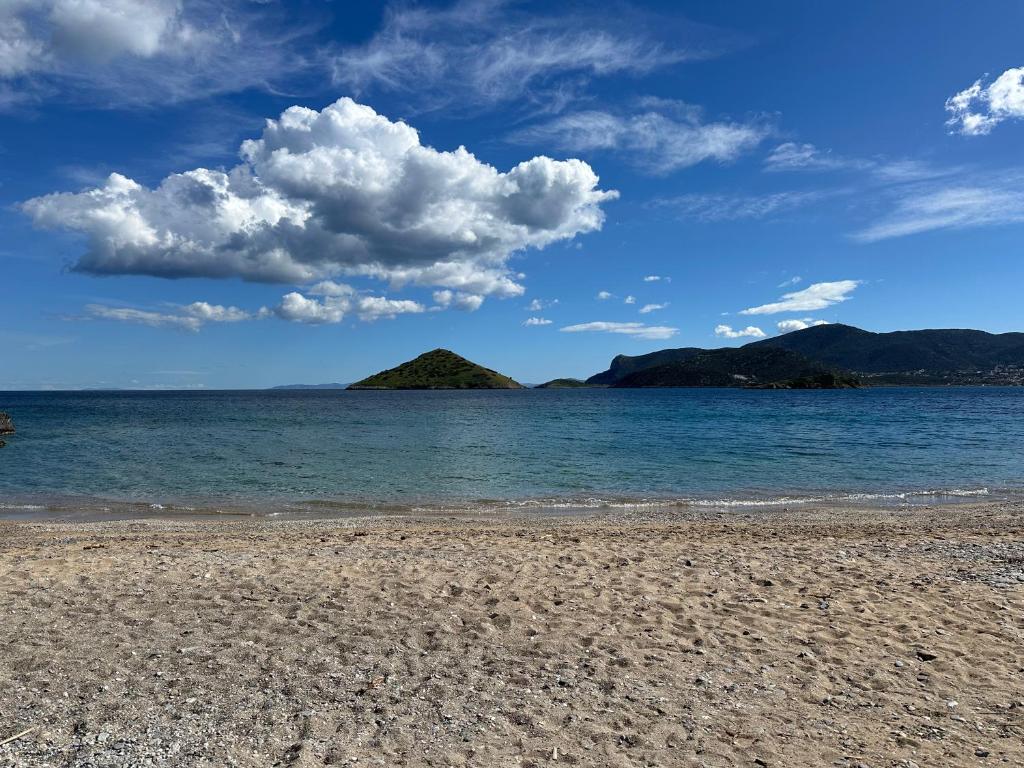 uma praia arenosa com ilhas na água em Becool Apartment em Porto Rafti