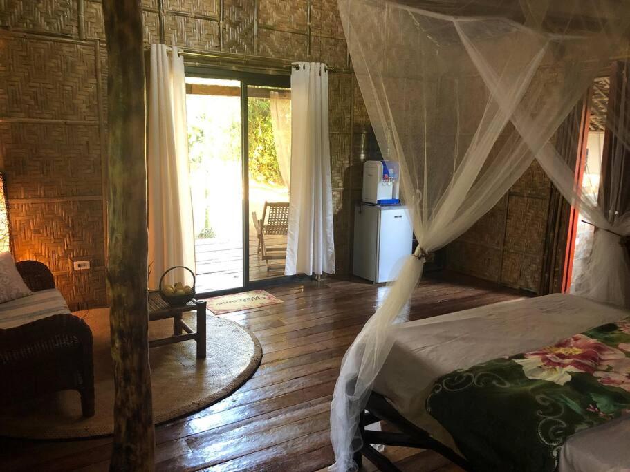 Schlafzimmer mit einem Bett mit Moskitonetz in der Unterkunft Maison bamboo, in Pila