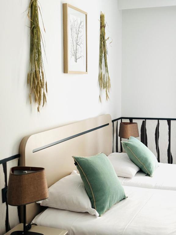 two beds in a room with plants on the wall at Hôtel De La Marine in Arromanches-les-Bains