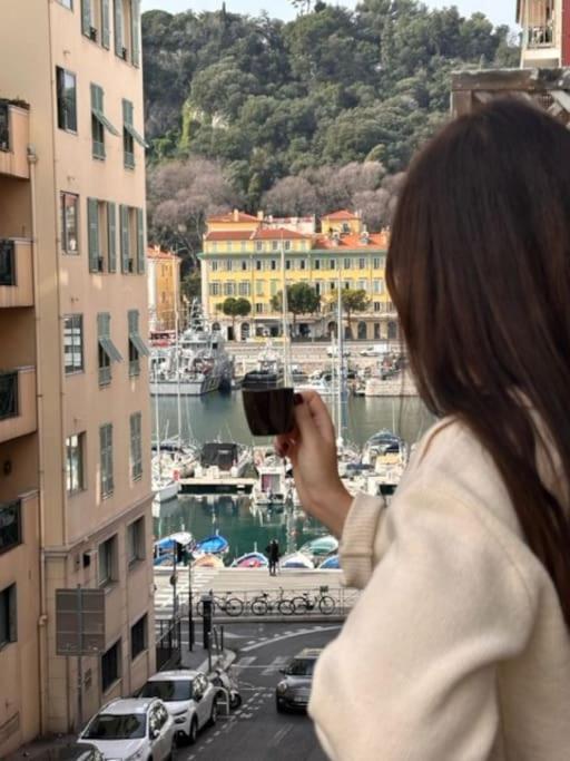 a woman taking a picture of a harbor from a building at Vue sur le Port Lympia charmant studio in Nice