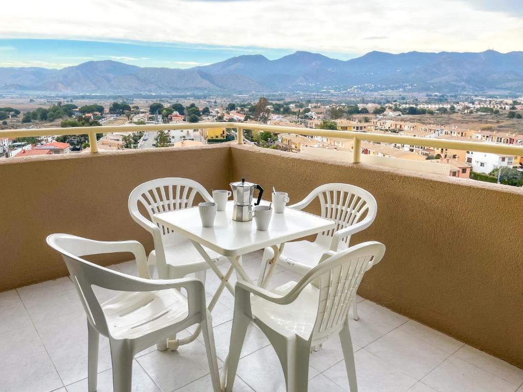 d'une table et de chaises blanches sur un balcon avec vue. dans l'établissement Apartamentos Benicassim 3000, à Benicàssim