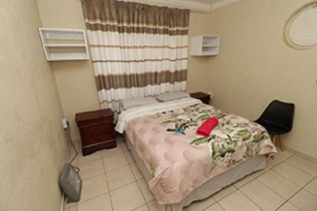 1 dormitorio con 1 cama y 1 silla en Las Palmas Day & Night Guest House, en Pretoria