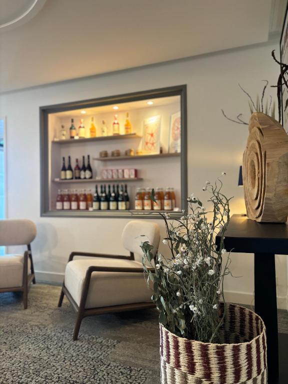a room with a couch and a shelf with bottles at Hôtel De La Marine in Arromanches-les-Bains