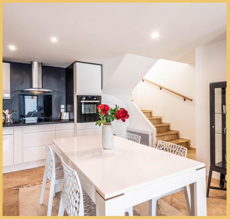 a kitchen with a white table with a vase of flowers on it at Appart T3 Luxe Douvaine in Douvaine