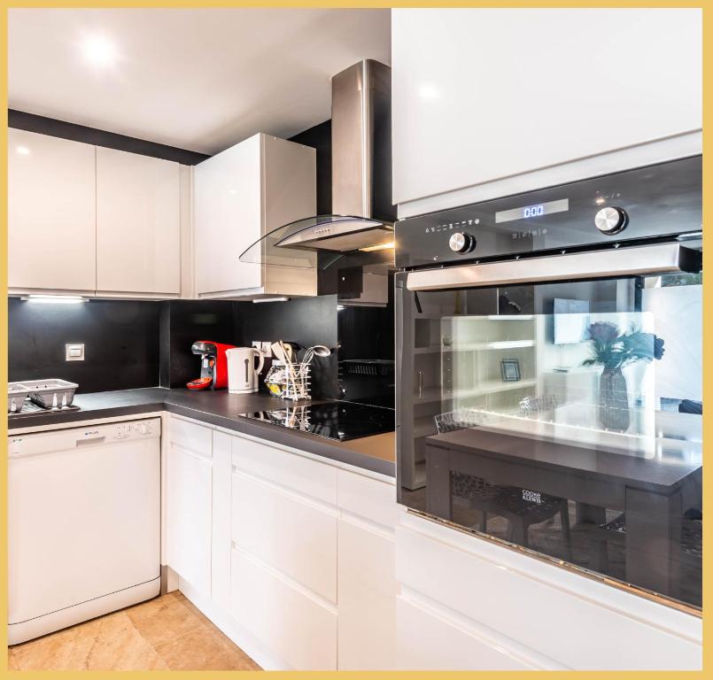 a kitchen with white cabinets and an oven at Appart T3 Luxe Douvaine in Douvaine