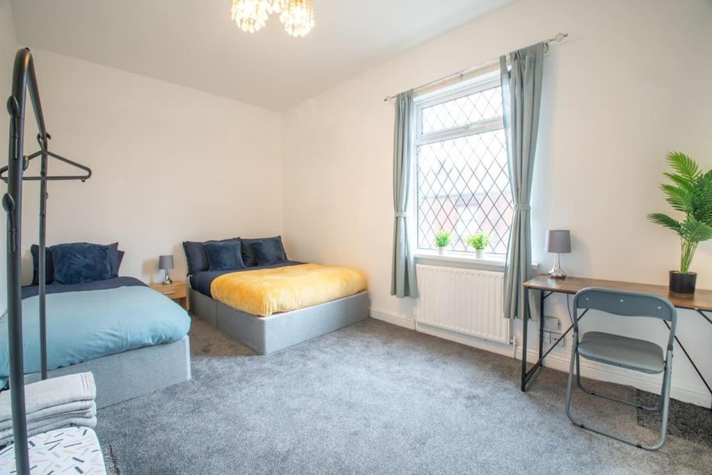 a bedroom with two beds and a desk and a window at Rochdale Train STN, Large House in Rochdale