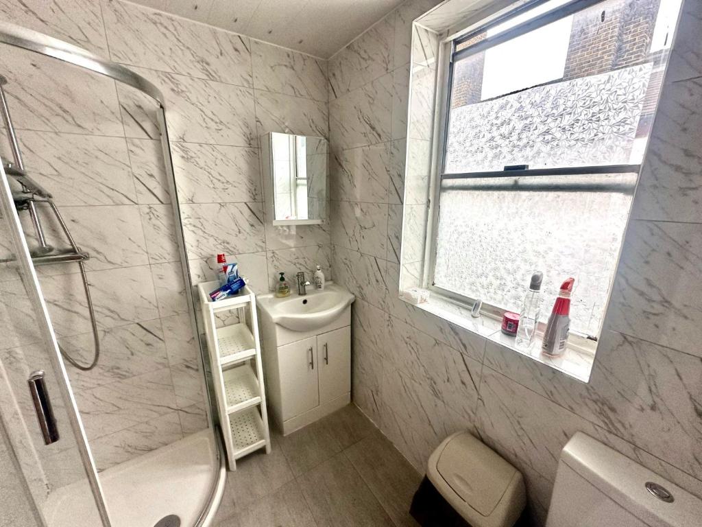 biała łazienka z prysznicem i umywalką w obiekcie Bethnal Green Rooms R5 w Londynie