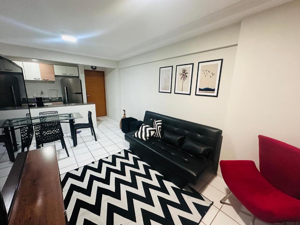 uma sala de estar com um sofá preto e uma mesa em Apartamento 2 quartos na Jatiúca em Maceió