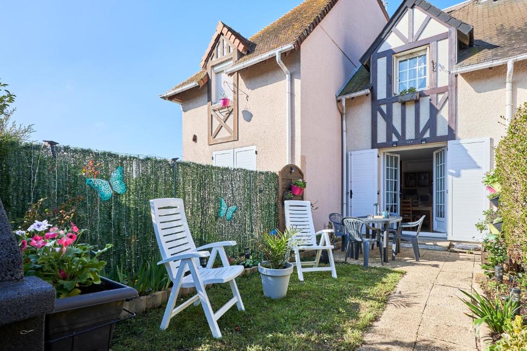 une cour avec des chaises, des tables et une clôture dans l'établissement La Villa Fleurie - Appt à 50m de la plage, à Courseulles-sur-Mer
