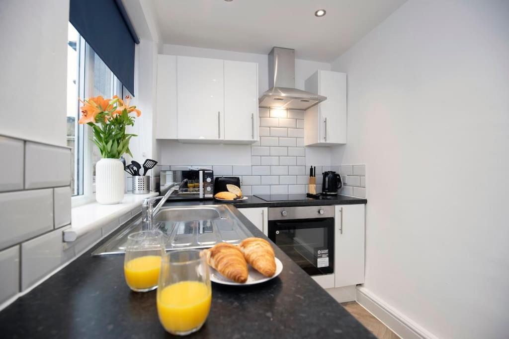 a kitchen with two glasses of orange juice and croissants at HC Property - Cromwell Avenue in Newcastle upon Tyne