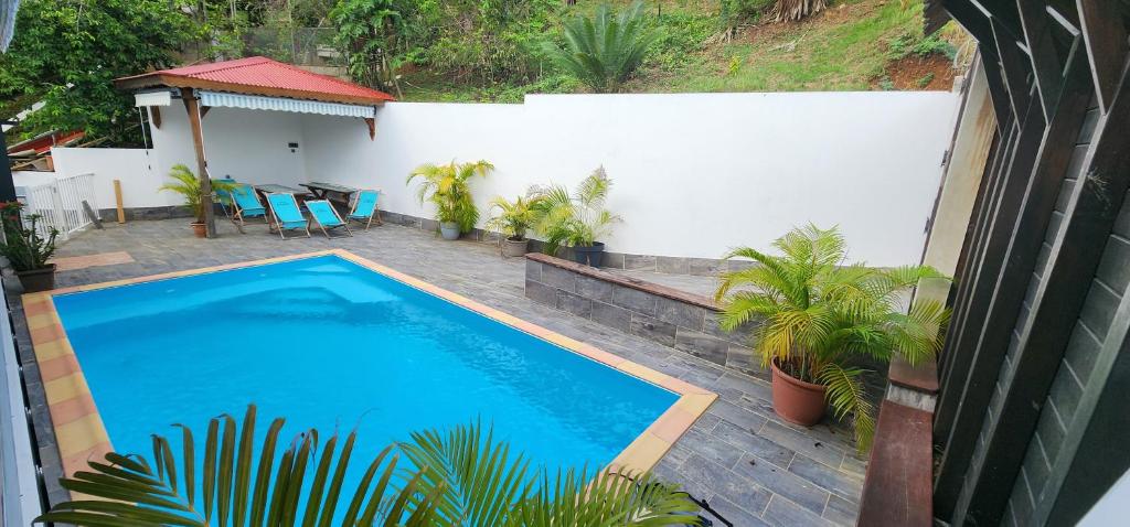 a swimming pool in a backyard with a table and chairs at La PAPAYERAIE in Le Marin