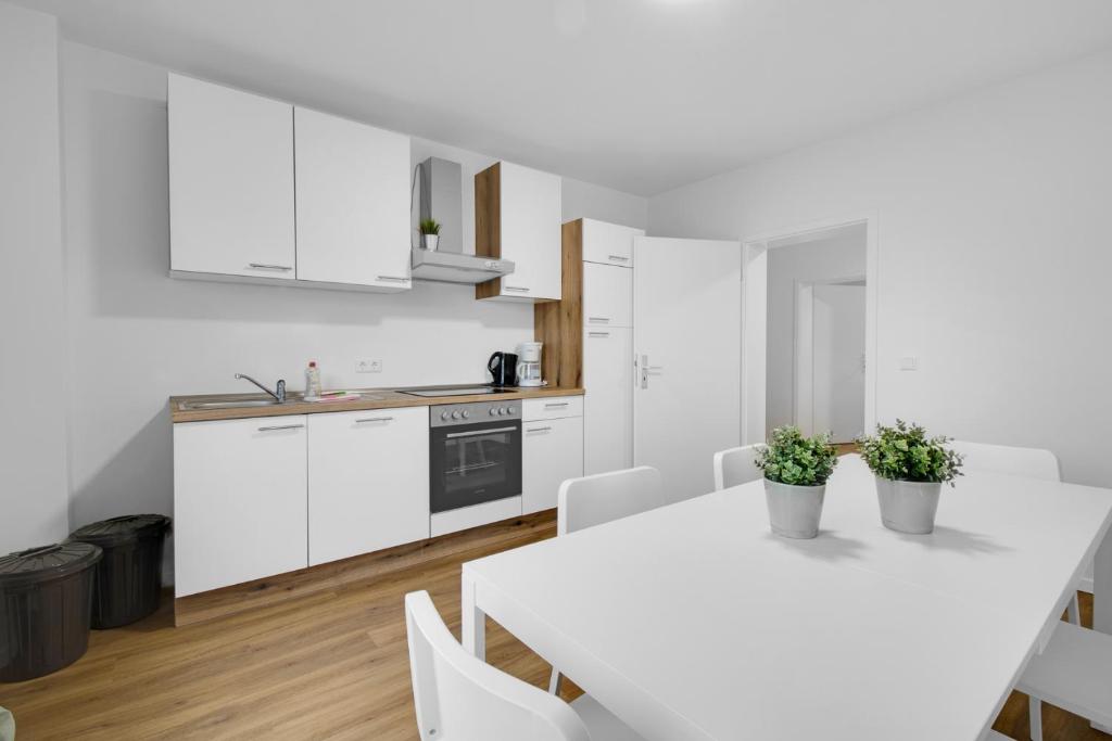 a kitchen with white cabinets and a white table and chairs at Business-Apartment in Lippstadt in Lippstadt