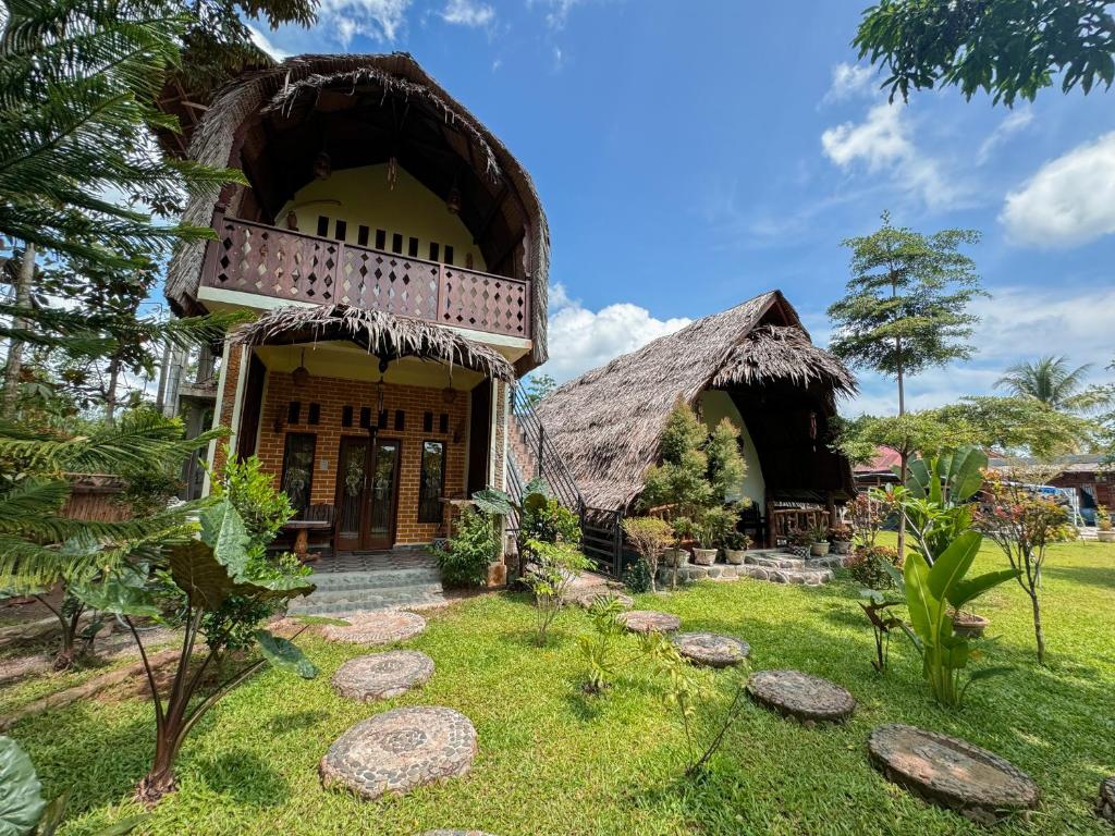 a house with a thatched roof and a yard at Sumatra Orangutan Treks Villa in Timbanglawang
